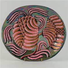 a decorative plate with pink and brown designs on the front, sitting on a white surface