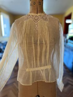 "A sweet Edwardian blouse in beautiful condition.  Made of a creamy silk organdy with tiny floral pattern, the blouse has gathers at the front waist, and filet lace and pintucks at the neckline.  There is a small flower embroidered at the centre front. Press studs at the rear, full sleeves and matching filet lace at the cuff. In excellent condition  Size medium.  Bust 36\" Waist 36\" Length 19\" Sleeve length 23\"" Elegant Lace Work Blouse For Daywear, Classic Lace Blouse, Sheer Fitted Blouse For Daywear, Fitted Sheer Blouse For Daywear, Sheer Blouse For Daywear, Elegant Long Sleeve Blouse With Yoke Detail, Feminine Sheer Blouse For Daywear, Sheer Lace Blouse For Daywear, Lace Top For Daywear