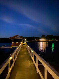 a long pier with lights at night on the water