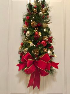 a christmas tree decorated with red and gold ornaments is hanging on the front door,