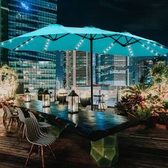 an outdoor dining area with tables, chairs and umbrellas on the deck at night