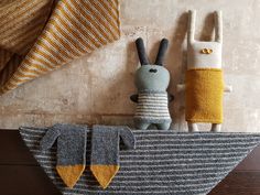 two stuffed animals sitting on top of a wooden boat next to a striped pillow and blanket