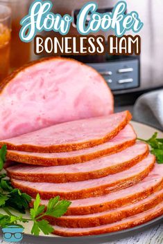 ham sliced up on a plate with parsley next to it and the words slow cooker boneless ham