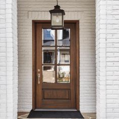 the front door to a house with a lantern hanging from it's sidelight