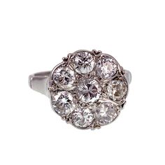 "Although diamond engagement rings among the aristocracy were common from the 15th century and on, it wasn't a widespread practice until the Victorian Era. A popular design was the \"daisy\", a solitaire diamond surrounded by smaller diamonds to represent a flower. Daisies were associated with loyalty, purity and innocence, the very attributes sought after in a new bride. Today, this style of ring is not reserved for matrimonial wear only. Cocktail rings and rings intended for the middle or index fingers are often designed in the flower-like shape, and are appropriate to wear for any occasion. This ring, made of an impressive 1.30 total carats in diamonds, is set in platinum, giving it an icy cold feel, just as if a daisy was caught in a winter storm, freezing the beautiful blossom in plac Memento Mori Ring, Buckle Ring, Cluster Engagement Ring, Art Nouveau Jewelry, Solitaire Diamond, 15th Century, Round Brilliant Cut Diamond, Cluster Ring, Victorian Era