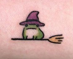 a small green frog with a purple hat on it's head