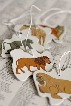 four different animal shaped tags on top of an open book with white string hanging from them