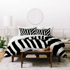 a zebra print comforter on a bed in a white room with a round mirror