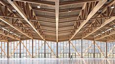 the inside of a building with large windows and lots of wood planks on the ceiling