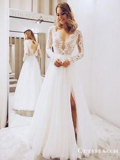 a woman standing in front of a mirror wearing a white wedding dress with long sleeves