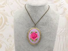 "This is a vintage inspired large rose cameo locket necklace. The beautiful pink fuschia rose with lavender purple background cameo is set on the lace pattern design locket. The cameo necklace is such a romantic classical accessory to keep in your treasure box. The locket can put photos and mementos. It has beautiful engraving designs on both the front and back. The locket size is 50mm x 38mm and the inner size for picture is 35mm x 26mm. It is suspended on a antique brass chain with a lobster c