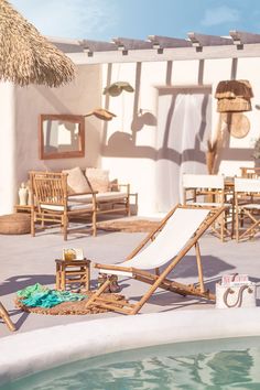 an outdoor pool with chairs, umbrellas and towels on the ground next to it