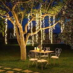 a table and chairs under a tree with lights