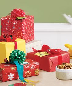 several wrapped presents sitting on top of a table next to a bowl filled with nuts