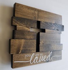 a wooden sign that says you are so loved on the side of a white wall