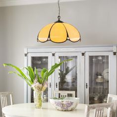 a dining room table and chairs with a yellow light hanging over it