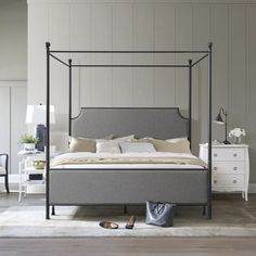 a bedroom with a four post bed and white dressers in the corner, along with a pair of shoes on the floor