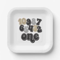 a white paper plate with numbers and numerals on it in black and gold