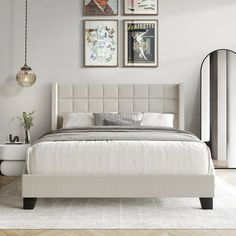 a white bed sitting in a bedroom next to two pictures on the wall above it