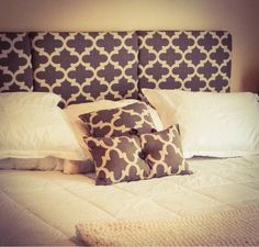 a bed with white and gray pillows on it's headboard in a bedroom