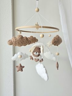 a crocheted teddy bear is hanging from a mobile with clouds and stars on it