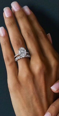 a woman's hand with two engagement rings on her left and the other hand is holding