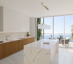 a kitchen with marble counter tops and an island in front of large windows overlooking the ocean