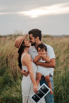 a man, woman and child are standing in tall grass with their arms around each other