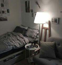 a bed sitting next to a gray couch in a living room under a white lamp