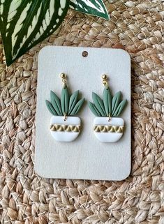 a pair of green and white earrings sitting on top of a piece of woven material