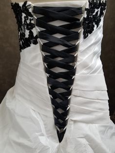 the back of a wedding dress with black and white laces on it's corsets