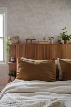 a bed with two pillows and some plants on the headboard in front of it