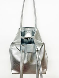 DESCRIPTION:Genuine leather tote bag, great for your essentials when you want a compact bag. Use around town for the weekend or an everyday bag. Perfect for travel as the bottom folds to pack flat.• Genuine leather with a metallic silver finish • Zipper closure OR Swivel lobster clasp and D-ring for closure• Interior pocket• Double leather strap with rivet detail• Reinforced leather bottom • Unlined with raw edges• Fringe detail on strap• Hand made• Made in USADIMENSIONS:9.5”H x 8”W x 4.5”D9.5" Bag Packs, Travel Free, Compact Bag, Genuine Leather Totes, Side To Side, Leather Cleaning, Everyday Bag, Open Top, Leather Tote Bag