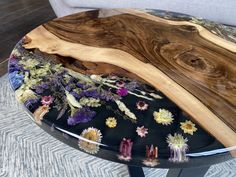 a table made out of wood and glass with flowers on the top, sitting on a carpeted floor