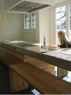 a woman sitting at a kitchen counter looking out the window