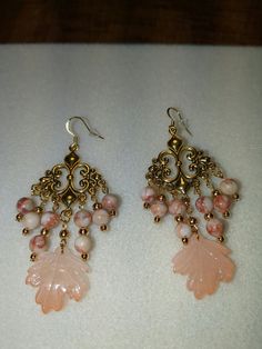 Beautiful peach pink glass leaves are the focal below red line jasper and gold beads of these elegant chandelier earrings. Includes silicone stoppers. Elegant Pink Chandelier Earrings With Dangling Beads, Pink Pierced Dangle Chandelier Earrings, Elegant Chandeliers, Red Line, Peach Pink, Pink Glass, Chandelier Earrings, Gold Beads, Jewelry Ideas