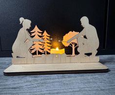 a wooden cutout of two people sitting at a table with a candle in front of them