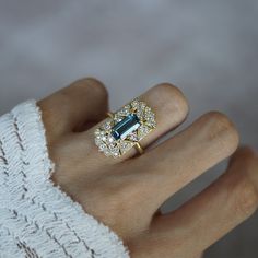 Read about our payment plans before proceeding. A ring that beautifully captures the ethereal allure of vintage design with a touch of celestial inspiration. This exquisite piece features a captivating emerald-cut London Blue Topaz at its center, radiating a deep, mesmerizing blue reminiscent of twilight skies. Surrounding the gemstone is a cluster of sparkling diamonds, each one set in a delicate, vintage-inspired gold setting that evokes the timeless beauty of heirloom jewelry. The intricate details of the gold filigree, combined with the serene blue of the topaz, create a sense of floating among the clouds, making this ring a perfect choice for those who dream of vintage charm with a modern twist. All orders come in our Tippy Taste ring box. This ring is handmade and designed in NYC. 14 Celestial Inspiration, Among The Clouds, Heirloom Jewelry, Twilight Sky, Heirlooms Jewelry, Gold Filigree, London Blue Topaz, London Blue, Gold Set