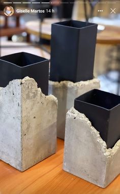 three cement vases sitting on top of a wooden table