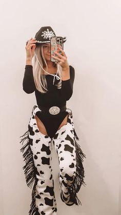 a woman in black and white outfit taking a selfie with her cell phone while wearing cow print leggings