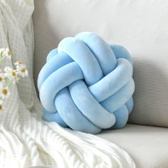 a blue knot pillow sitting on top of a white couch