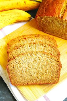 a loaf of banana bread sitting on top of a cutting board next to some bananas