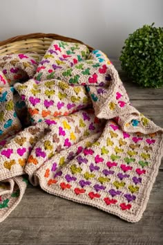 a crocheted blanket sitting on top of a wooden table next to a potted plant