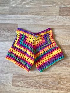 a pair of colorful knitted shorts laying on top of a wooden floor next to each other