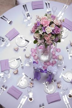 the table is set with purple and white flowers