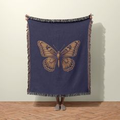 a woman standing in front of a wall with a butterfly tapestry on it