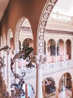 the inside of a large building with arches and columns on each side, looking down at an elaborately decorated staircase