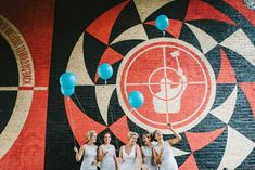 three women standing in front of a wall with balloons