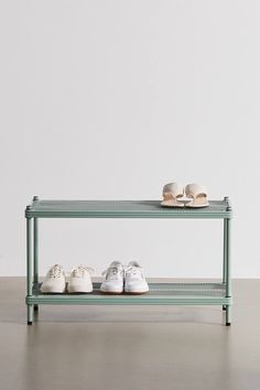 three pairs of shoes are sitting on a green shelf next to each other in front of a white wall