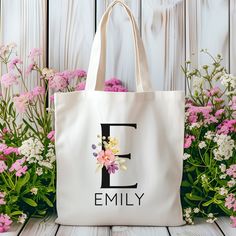 a tote bag with the letter e on it sitting in front of some flowers